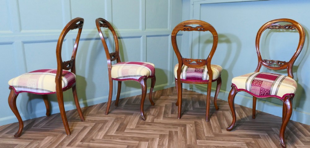 A set of four Victorian mahogany dining chairs featuring carved balloon-shaped backframes, cabriole front legs, and patterned upholstered seats. View V