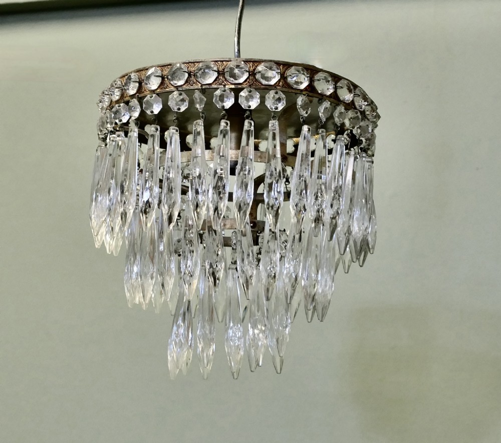 A petite tiered waterfall pendant chandelier featuring faceted cut glass droplets suspended from an ornate circular brass rim. View II