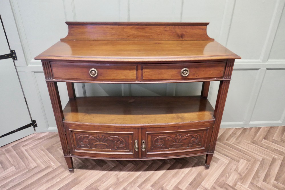 A carved warm brown walnut sideboard featuring two upper drawers, an open lower tier, two carved cupboard doors, fluted side columns, and a raised top gallery. View II