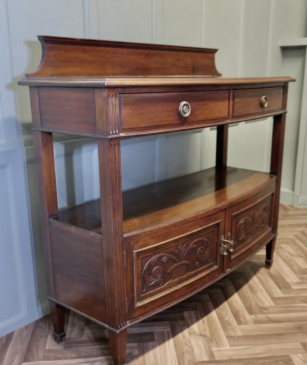 A carved warm brown walnut sideboard featuring two upper drawers, an open lower tier, two carved cupboard doors, fluted side columns, and a raised top gallery. View III