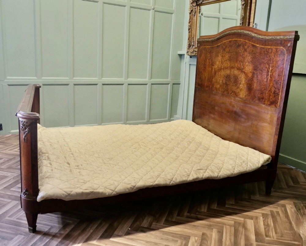 An Art Deco French style double bed featuring a shaped burr walnut headboard and footboard with gilt metal mounts. View II
