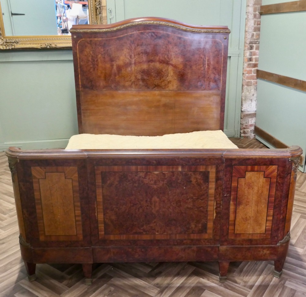 An Art Deco French style double bed featuring a shaped burr walnut headboard and footboard with gilt metal mounts. View V