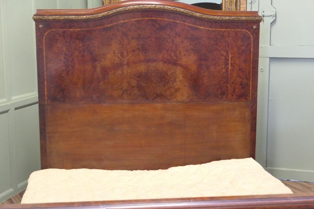 An Art Deco French style double bed featuring a shaped burr walnut headboard and footboard with gilt metal mounts. View VII