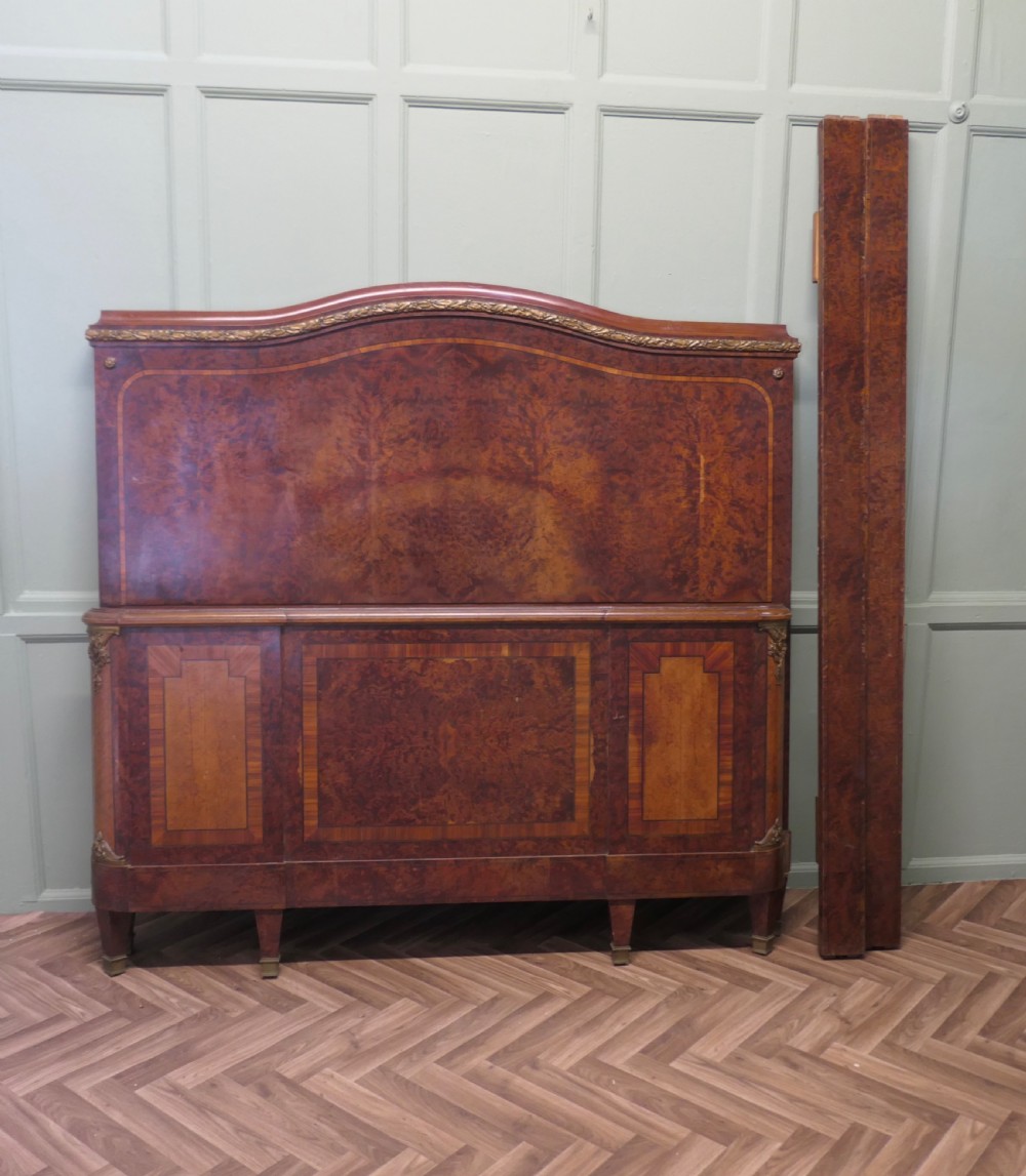 An Art Deco French style double bed featuring a shaped burr walnut headboard and footboard with gilt metal mounts. View IX
