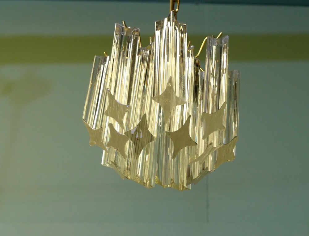 A set of three Art Deco style chandeliers featuring tiered vertical clear crystal prisms hanging from polished brass caps. View III