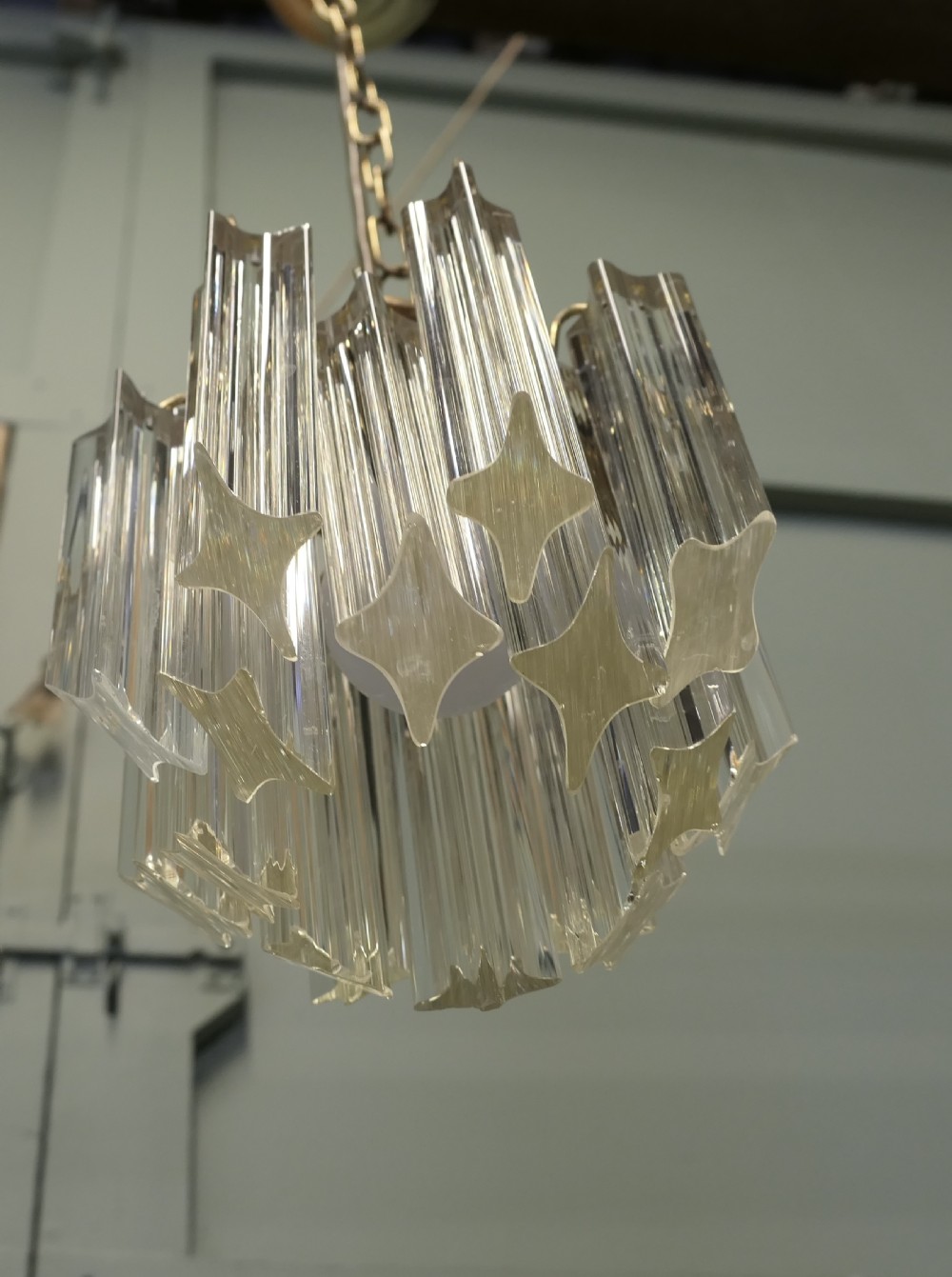 A set of three Art Deco style chandeliers featuring tiered vertical clear crystal prisms hanging from polished brass caps. View V