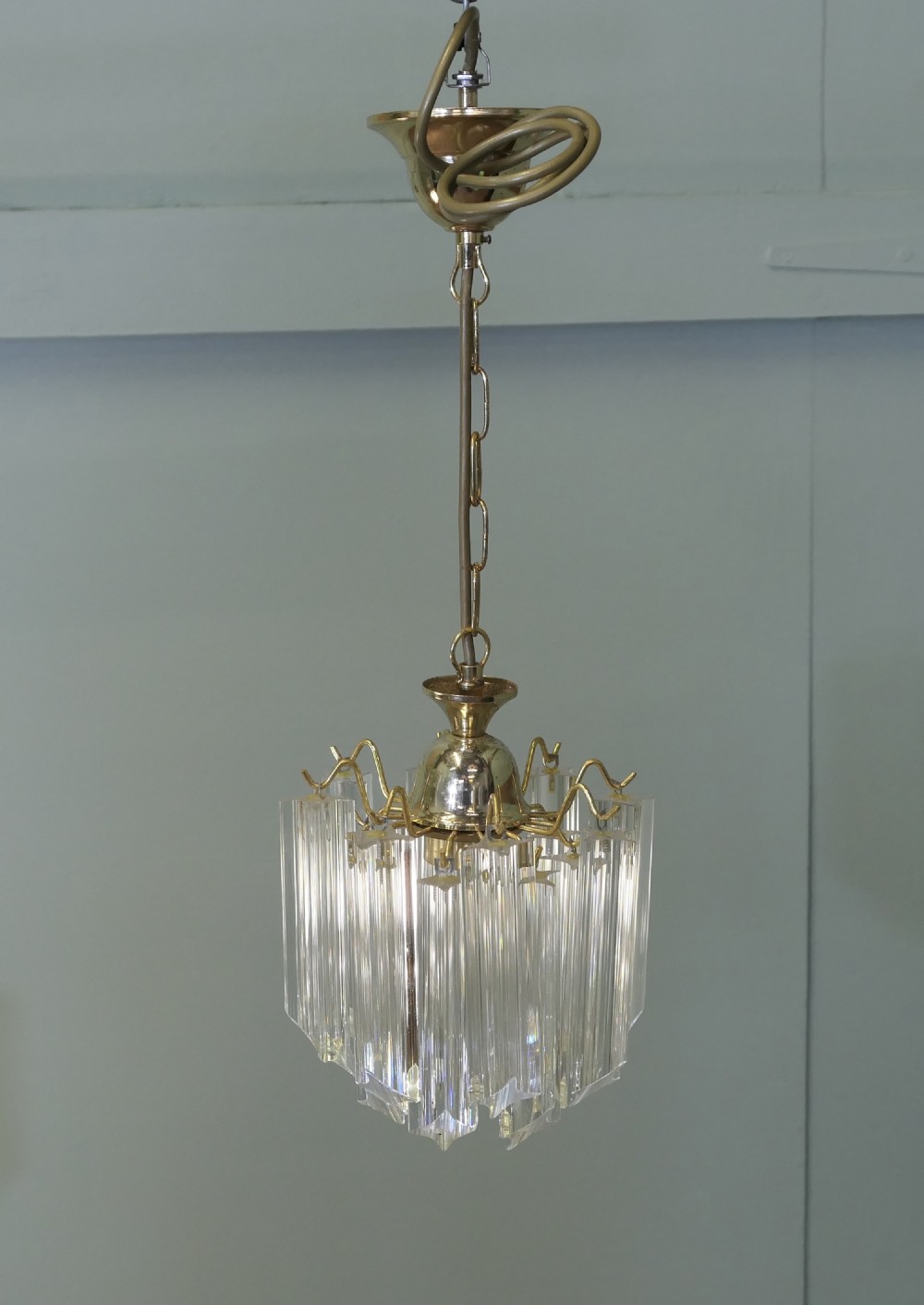 A set of three Art Deco style chandeliers featuring tiered vertical clear crystal prisms hanging from polished brass caps. View VIII