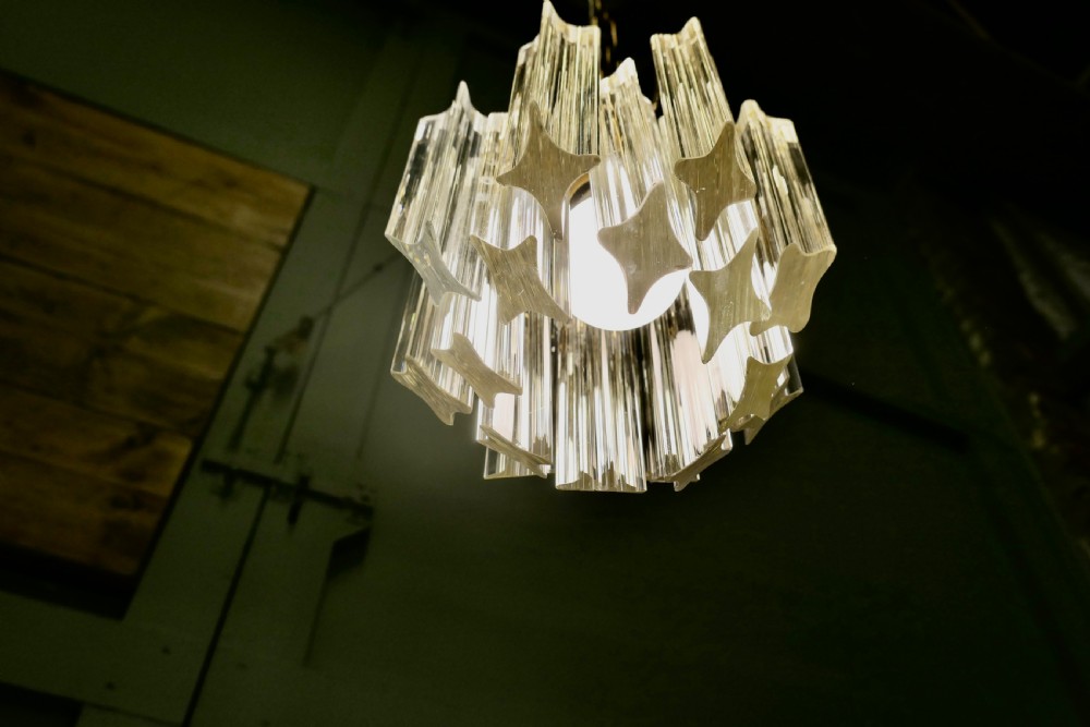 A set of three Art Deco style chandeliers featuring tiered vertical clear crystal prisms hanging from polished brass caps. View X