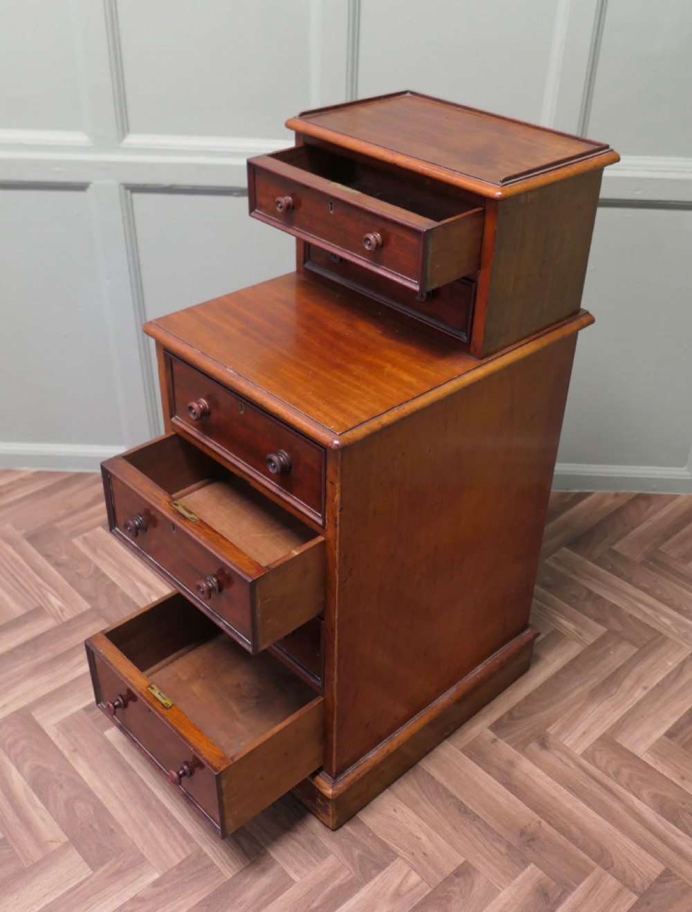 A tall Victorian mahogany side cabinet featuring six drawers in a two-tiered stepped design with turned wooden knobs and a plinth base. View VI