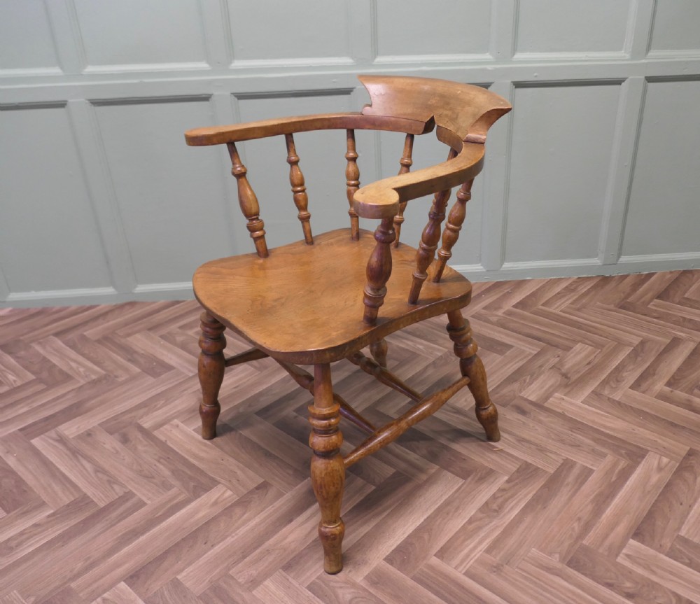 A 19th-century wooden smokers bow armchair featuring a curved crest rail, turned baluster spindles, a carved saddle seat, and turned legs. View III