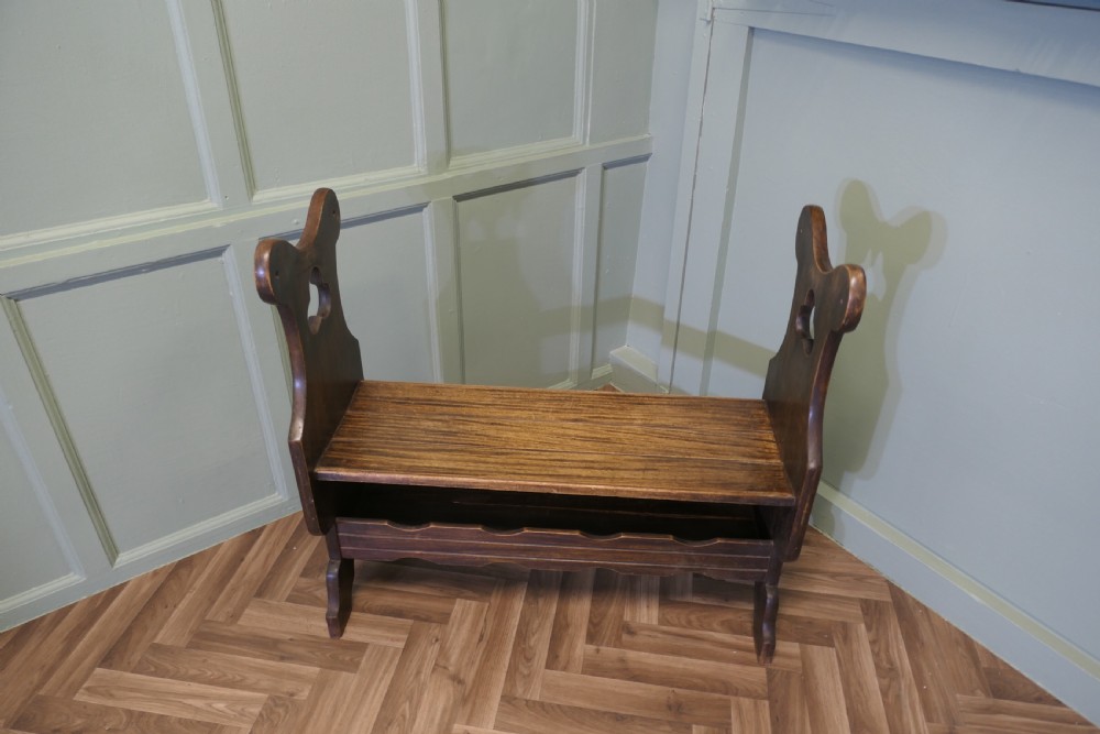 A dark walnut hall bench with high cutout side supports, a flat wooden seat, and a lower scalloped shelf for shoe storage. View II