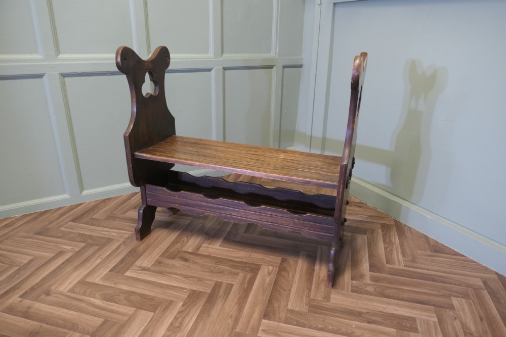 A dark walnut hall bench with high cutout side supports, a flat wooden seat, and a lower scalloped shelf for shoe storage. View VII