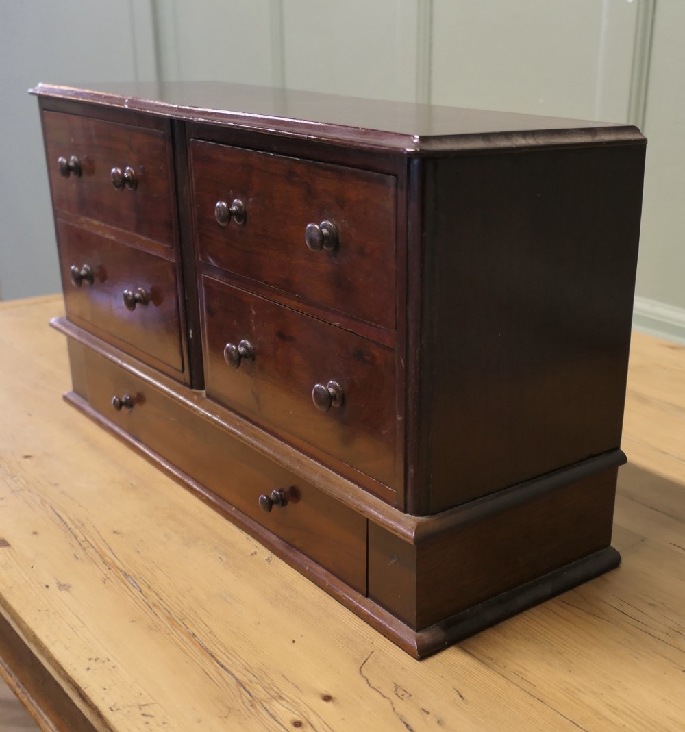 A mahogany desktop cabinet featuring five drawers with turned wooden handles arranged in two upper rows and one lower wide drawer. View III