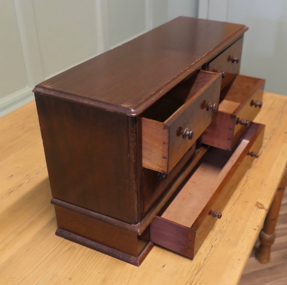 A mahogany desktop cabinet featuring five drawers with turned wooden handles arranged in two upper rows and one lower wide drawer. View VI