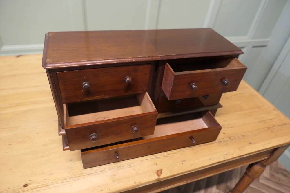A mahogany desktop cabinet featuring five drawers with turned wooden handles arranged in two upper rows and one lower wide drawer. View VII