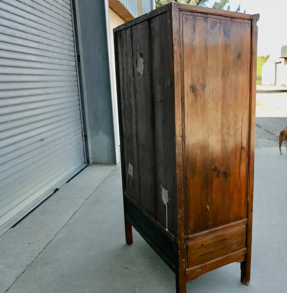 A tall warm brown teak cupboard featuring two upper panelled doors with brass hardware above ten small drawers arranged in two rows. View IV