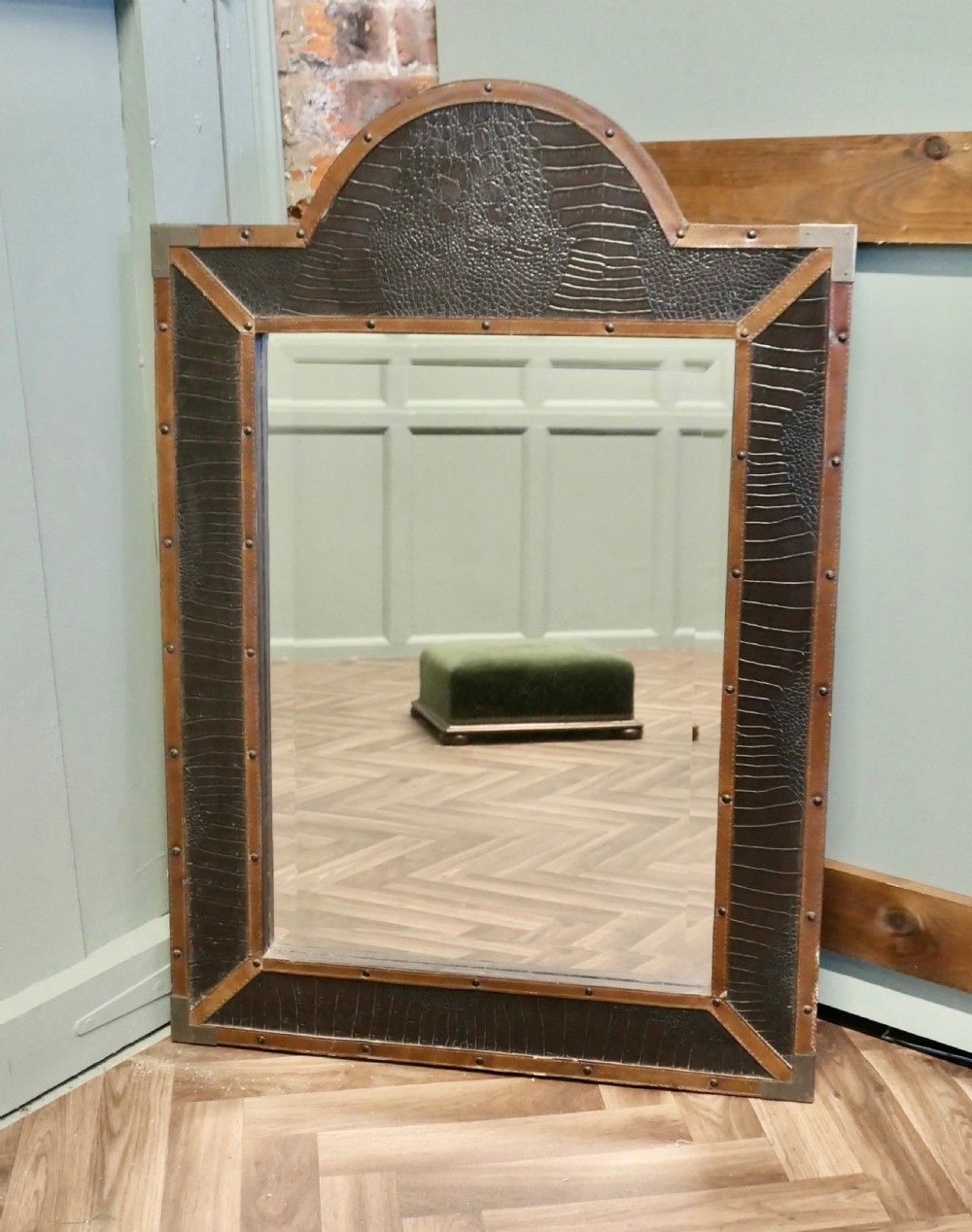 An Art Deco wall mirror featuring a dark crocodile-embossed leather frame with tan leather borders, brass stud details, and an arched crest. View II