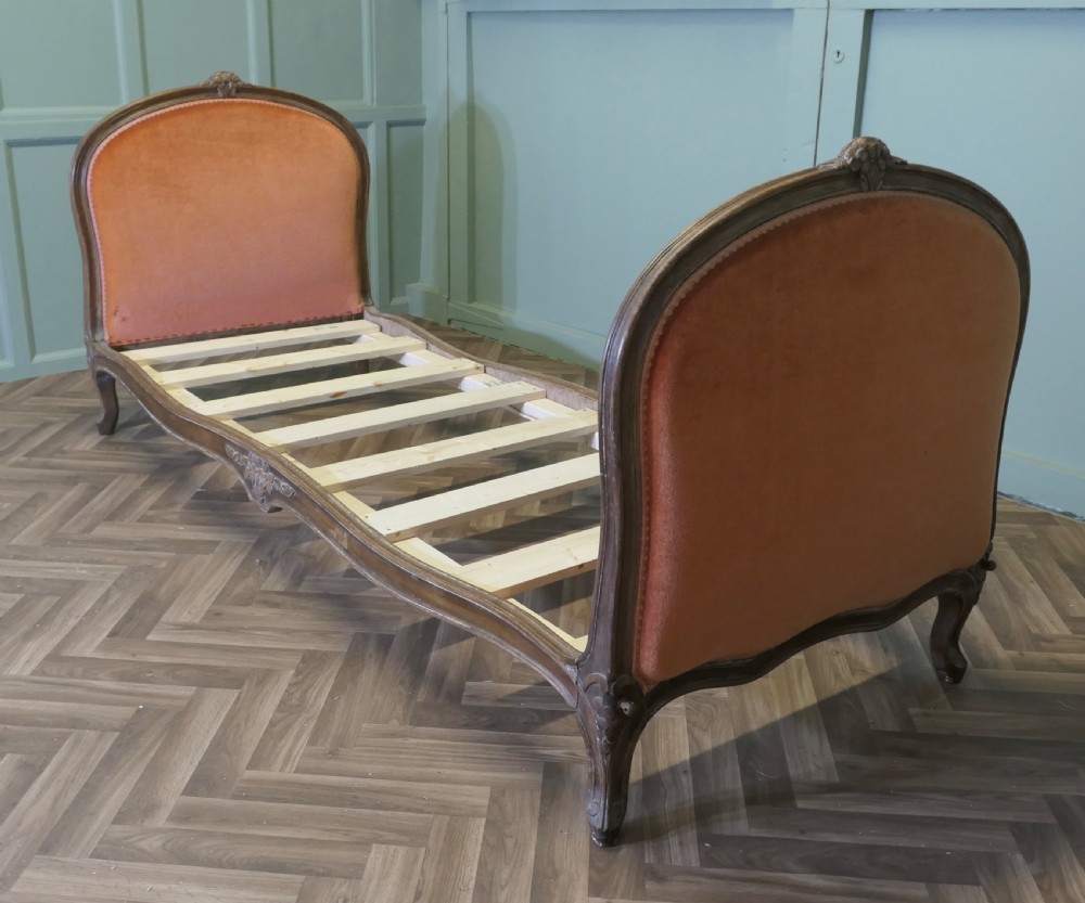 A 19th-century French carved wood daybed featuring raised terracotta velvet upholstered end panels and a tufted cream mattress cushion. View VII