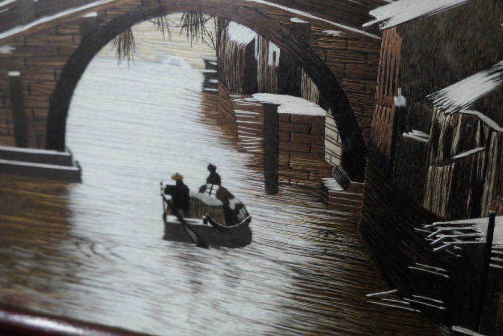 A detailed Chinese silk embroidery depicting a canal and boat scene set inside a dark carved hardwood table screen. View III