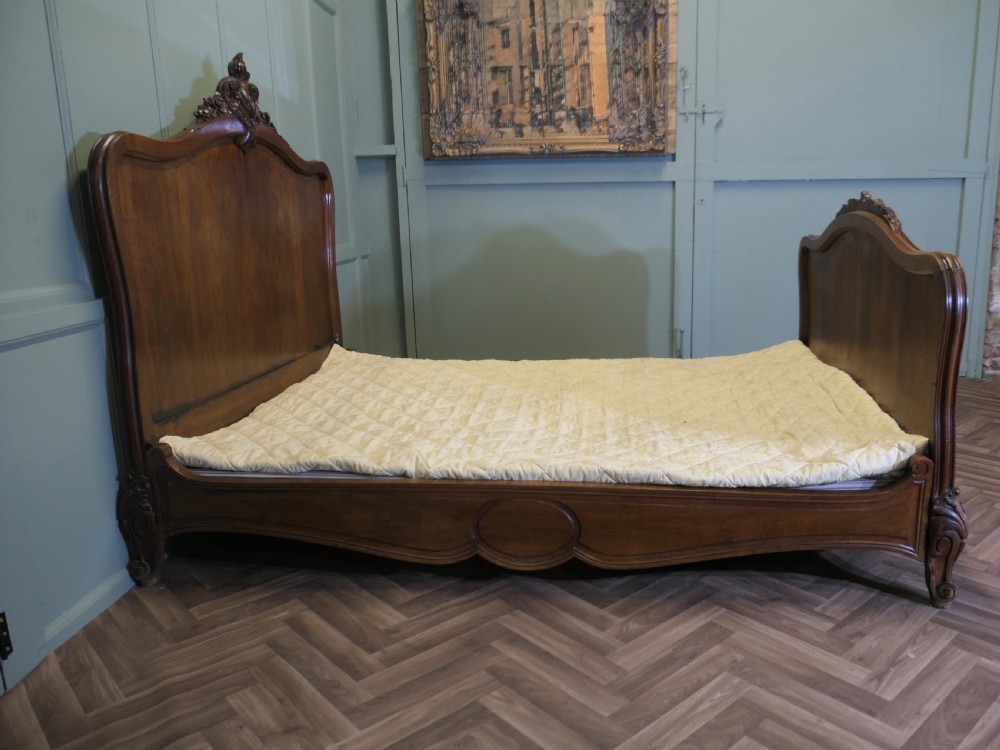 A Louis XV style carved golden walnut bed frame featuring arched headboard and footboard panels decorated with central rocaille motifs and cabriole feet. View III