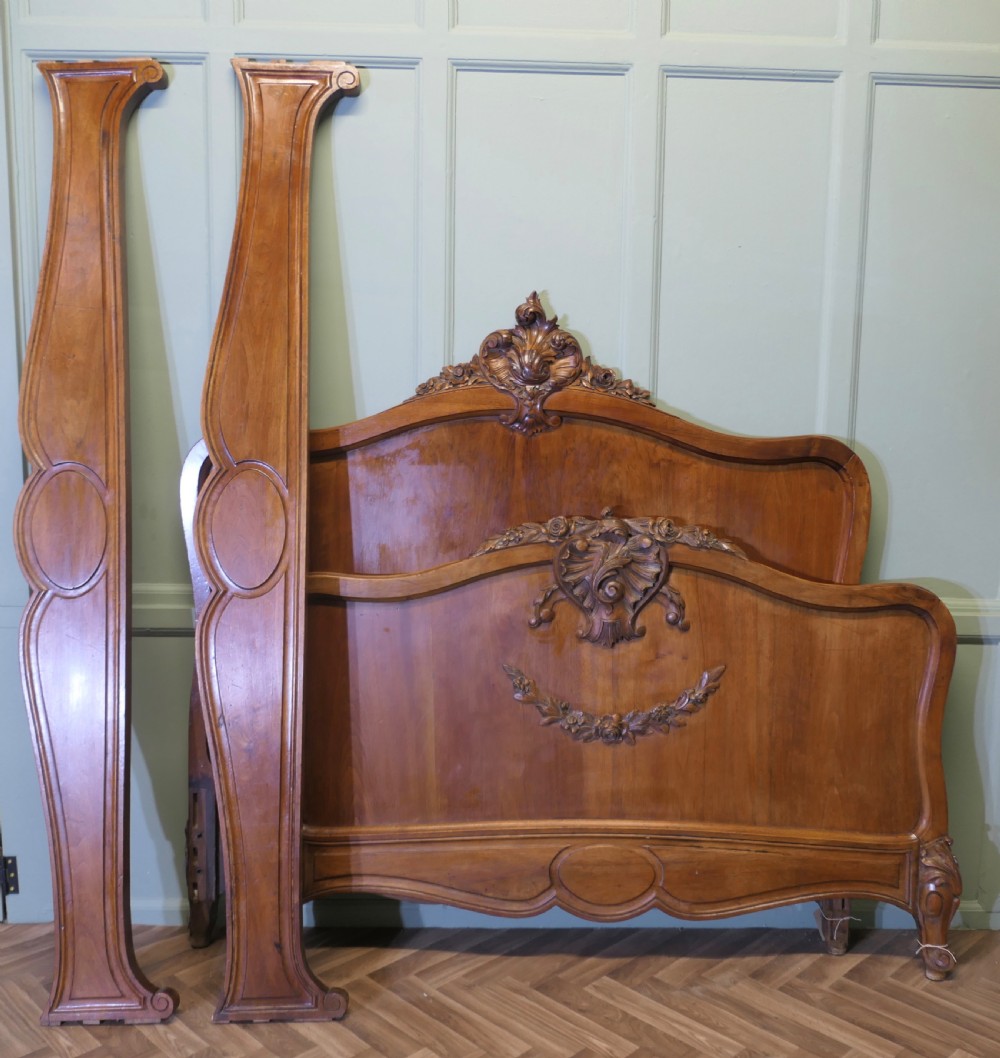 A Louis XV style carved golden walnut bed frame featuring arched headboard and footboard panels decorated with central rocaille motifs and cabriole feet. View IX