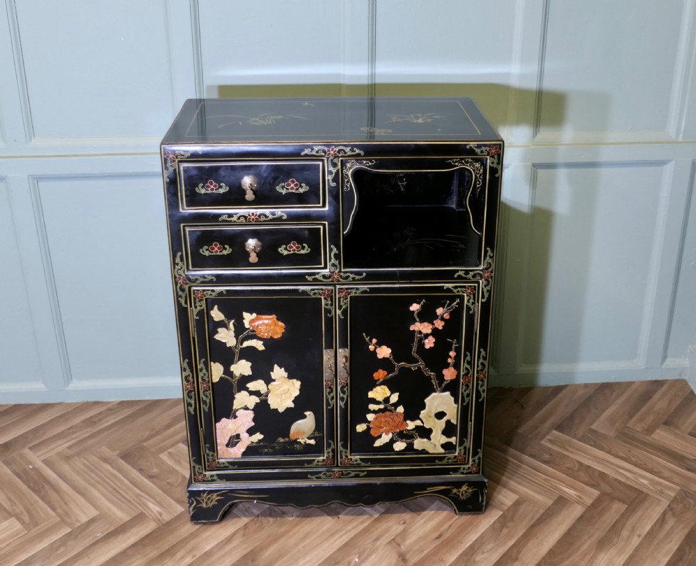 A black lacquered Chinoiserie cupboard featuring two drawers, an open upper display niche, and lower double doors decorated with floral and bird inlays. View III