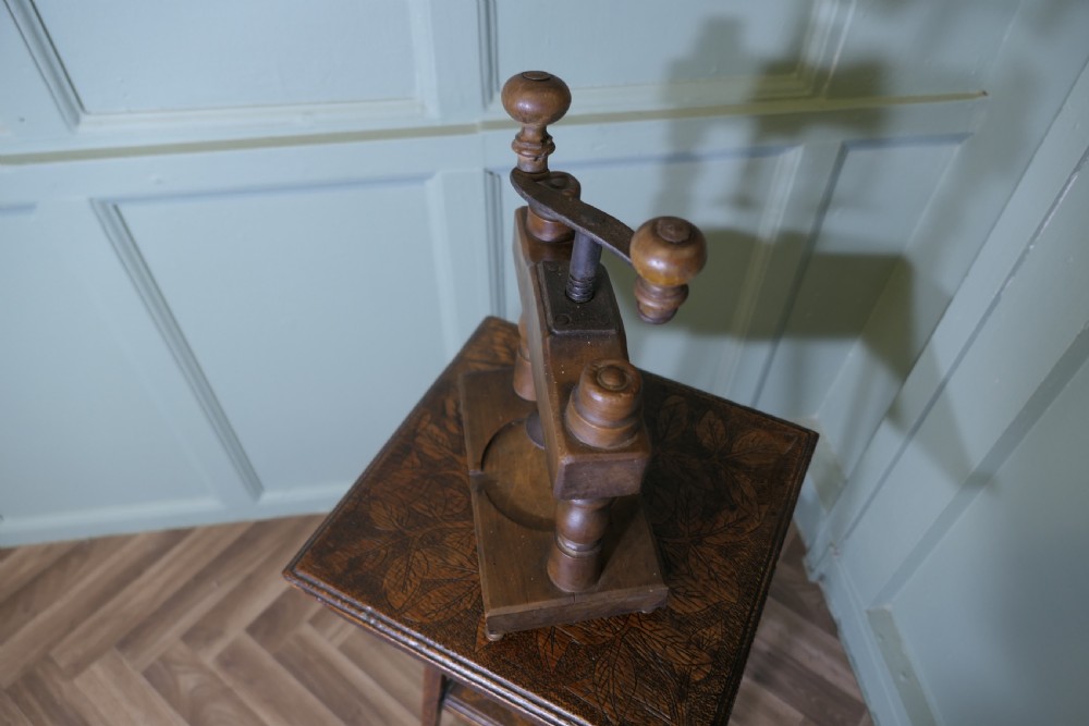 A nineteenth-century French wooden cheese press featuring turned upright columns, a hand-cranked screw mechanism, and a circular recessed base with a drainage channel. View III