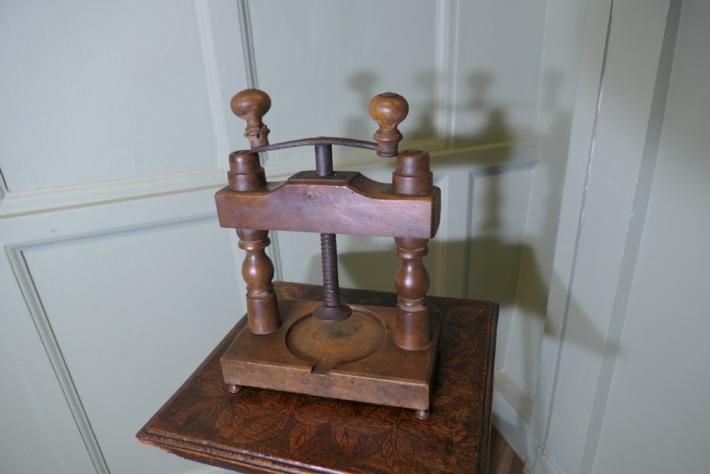 A nineteenth-century French wooden cheese press featuring turned upright columns, a hand-cranked screw mechanism, and a circular recessed base with a drainage channel. View V