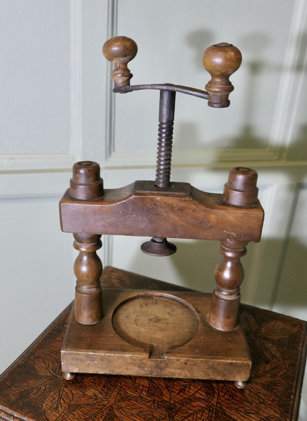A nineteenth-century French wooden cheese press featuring turned upright columns, a hand-cranked screw mechanism, and a circular recessed base with a drainage channel. View VI