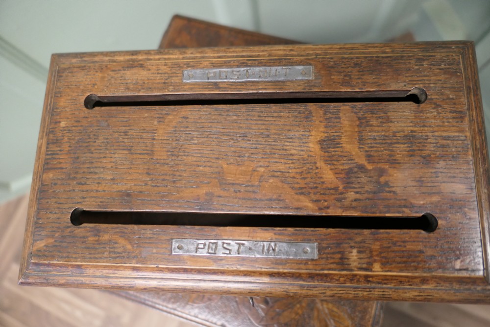 A rectangular golden oak correspondence letter box featuring top slots with metal plaques, a central brass keyhole escutcheon, and a moulded base. View II