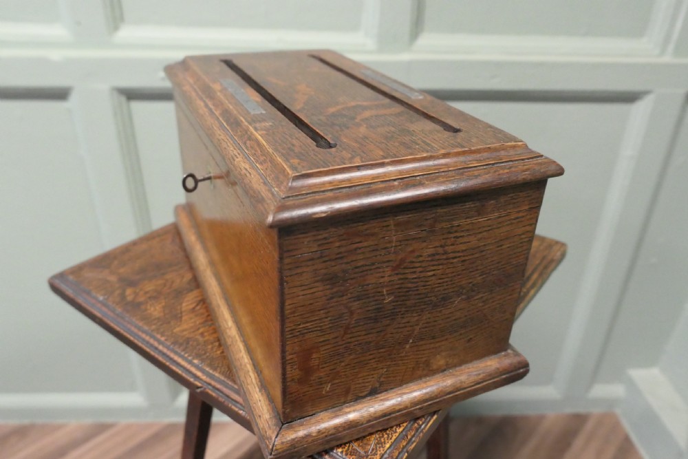 A rectangular golden oak correspondence letter box featuring top slots with metal plaques, a central brass keyhole escutcheon, and a moulded base. View V