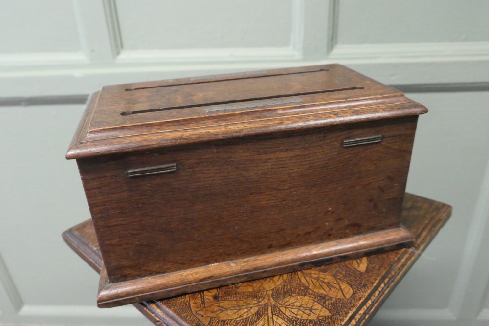 A rectangular golden oak correspondence letter box featuring top slots with metal plaques, a central brass keyhole escutcheon, and a moulded base. View VI