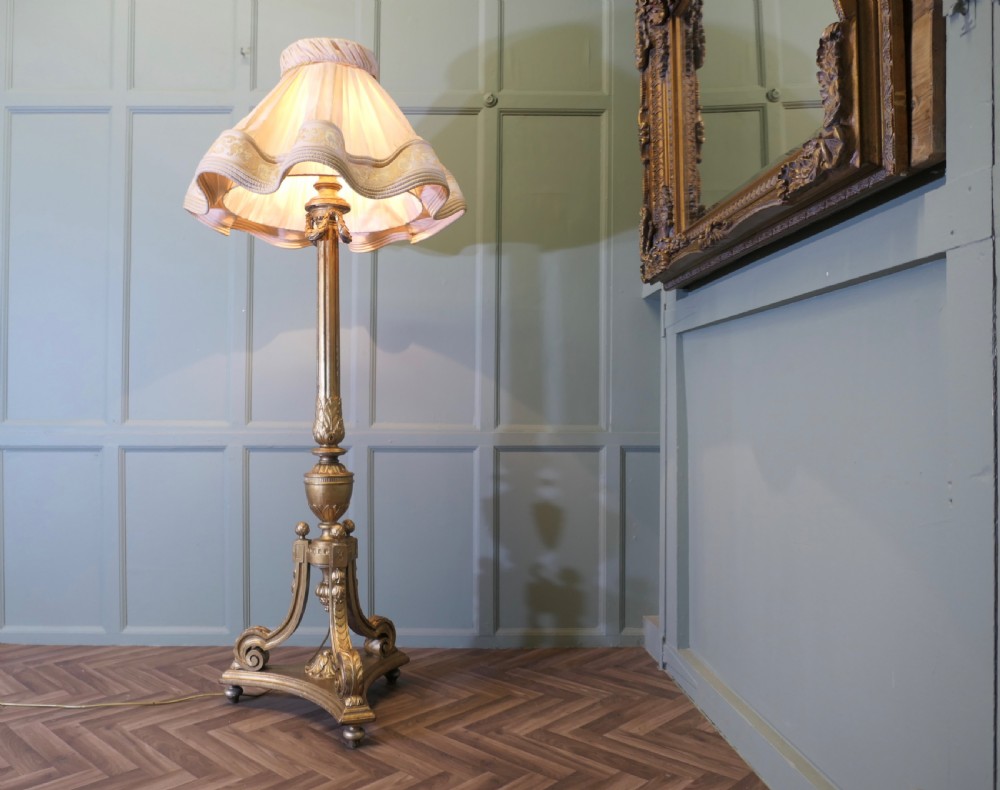 A tall antique carved giltwood floor lamp featuring a fluted column, scrolled tripod base, and a pleated cream fabric shade with embroidered trimming. View II