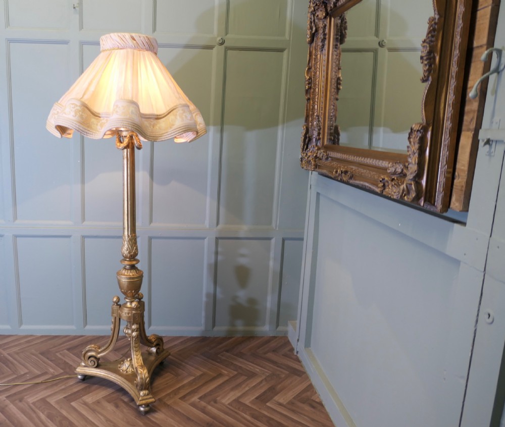 A tall antique carved giltwood floor lamp featuring a fluted column, scrolled tripod base, and a pleated cream fabric shade with embroidered trimming. View V