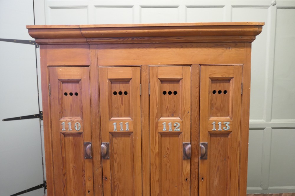A four-door golden pine sports locker featuring numbered metal tags, circular ventilation holes, and brass fittings. View VII