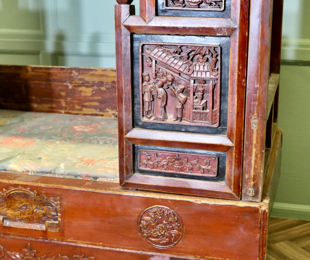 An antique Chinese red lacquered canopy bed decorated with carved gilded relief panels and lattice side screens. View III