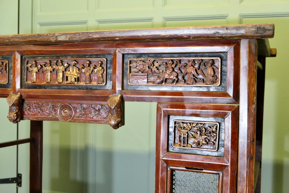 An antique Chinese red lacquered canopy bed decorated with carved gilded relief panels and lattice side screens. View V