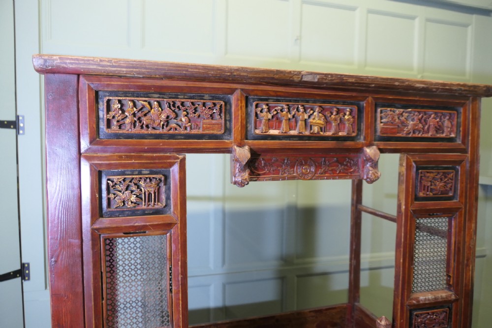 An antique Chinese red lacquered canopy bed decorated with carved gilded relief panels and lattice side screens. View IX