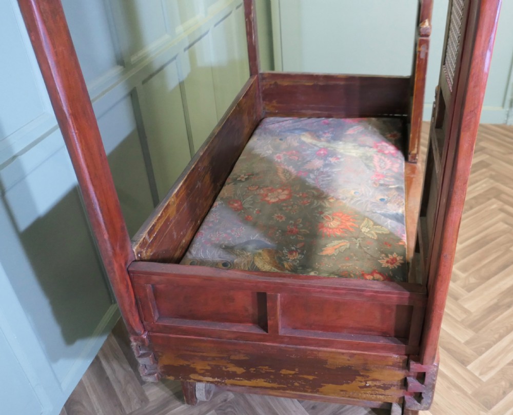 An antique Chinese red lacquered canopy bed decorated with carved gilded relief panels and lattice side screens. View X