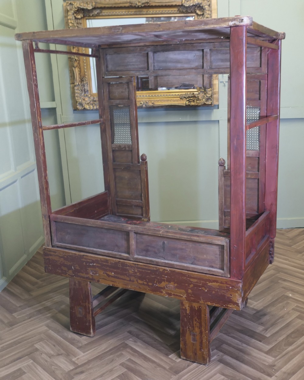 An antique Chinese red lacquered canopy bed decorated with carved gilded relief panels and lattice side screens. View XI