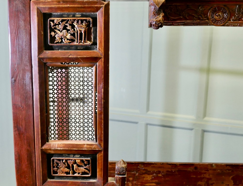 An antique Chinese red lacquered canopy bed decorated with carved gilded relief panels and lattice side screens. View XII