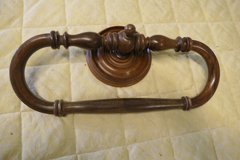 A turned walnut wall-mounted bed canopy frame with a circular backplate and curved drapery hoop. View II