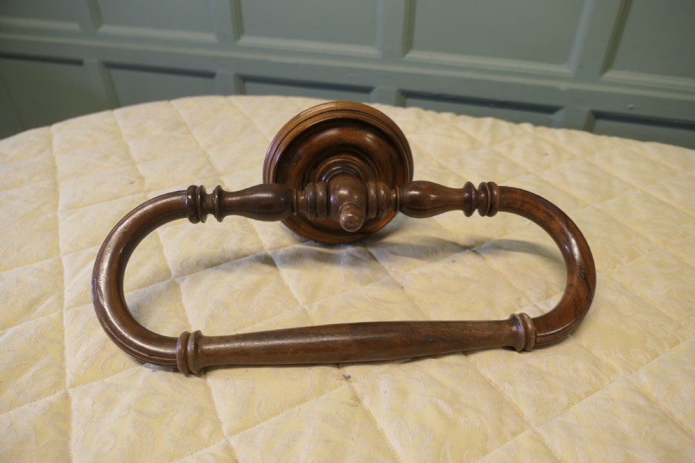 A turned walnut wall-mounted bed canopy frame with a circular backplate and curved drapery hoop. View V