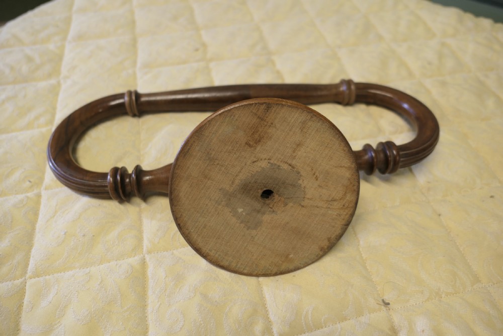 A turned walnut wall-mounted bed canopy frame with a circular backplate and curved drapery hoop. View VI