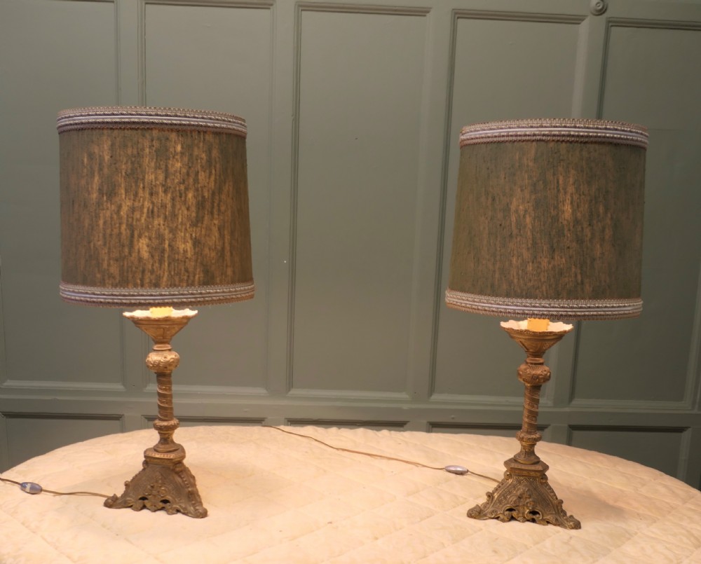 A pair of heavy French Gothic style brass table lamps featuring turned columns, ornate openwork bases, and green fabric shades. View II