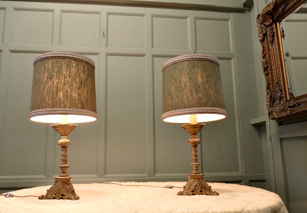 A pair of heavy French Gothic style brass table lamps featuring turned columns, ornate openwork bases, and green fabric shades. View VI