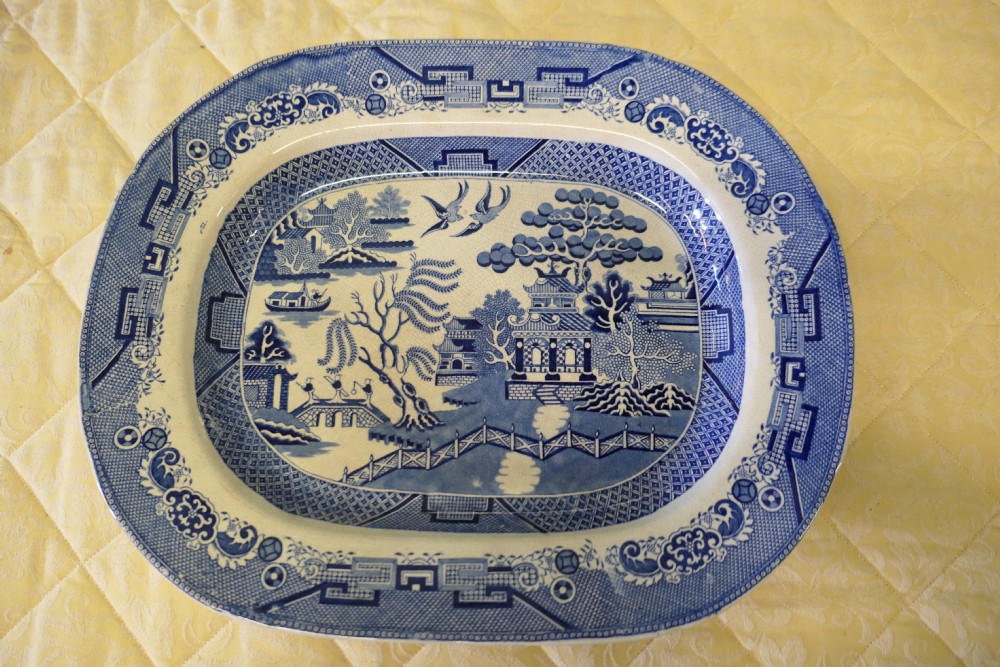 A large rectangular Victorian ironstone meat platter featuring a cobalt blue and white transfer printed Willow pattern landscape scene.