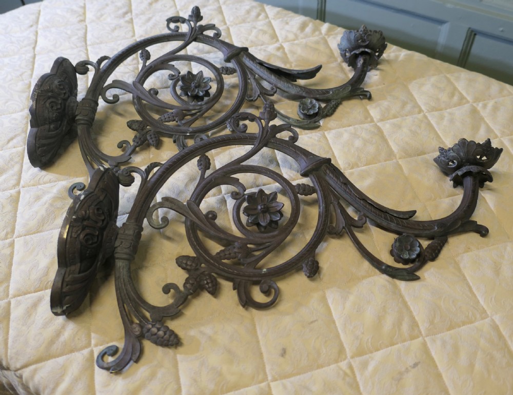 A pair of elaborate dark patinated French bronze wall brackets featuring scrollwork, floral rosettes, and pinecone motifs. View V
