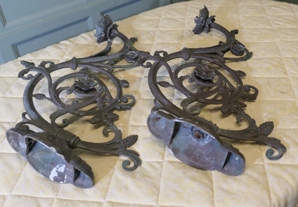 A pair of elaborate dark patinated French bronze wall brackets featuring scrollwork, floral rosettes, and pinecone motifs. View VI