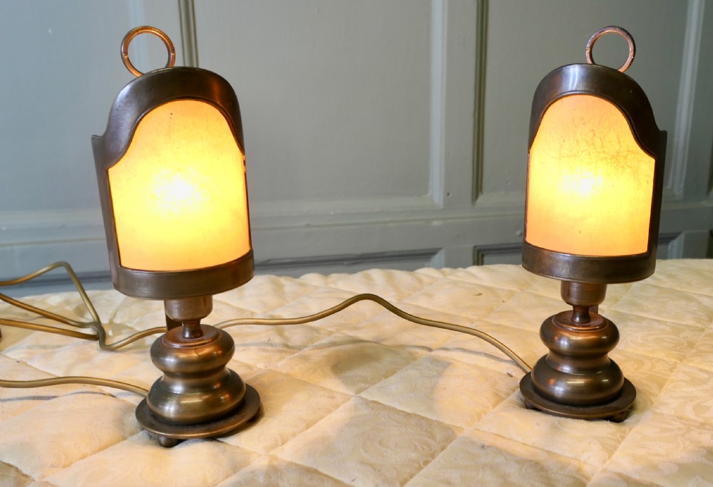 A pair of turned brass bedside lamps with railway lantern styled cowls, ring finials, and illuminated amber parchment shades. View VII
